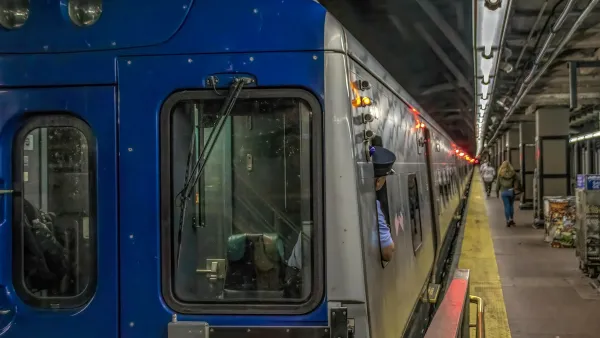 New York City subway train at station with operator looking back toward platform.