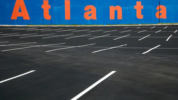 Empty asphalt parking lot with blue wall in background with Atlanta painted in orange letters.