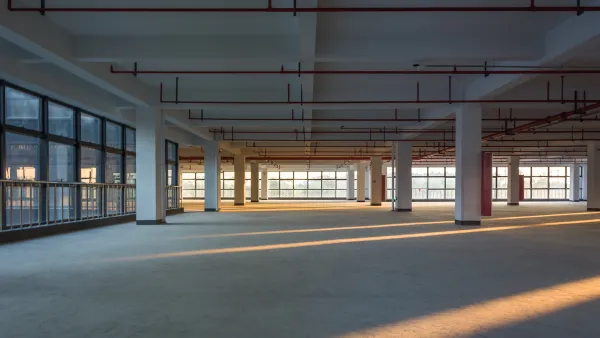 Large empty office building floor with columns and golden hour light.