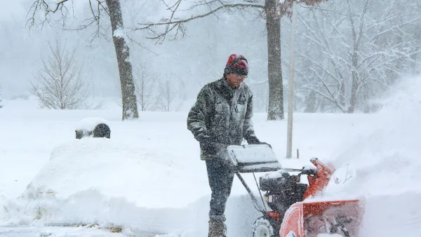 Man using snow plow during snowstorm.