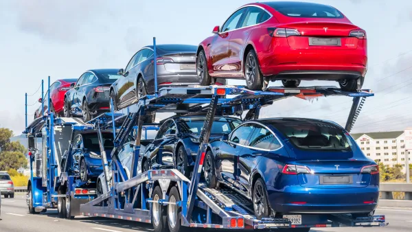 Red, grey, and blue Tesla cars on the back of a truck trailer in Burlingame, California