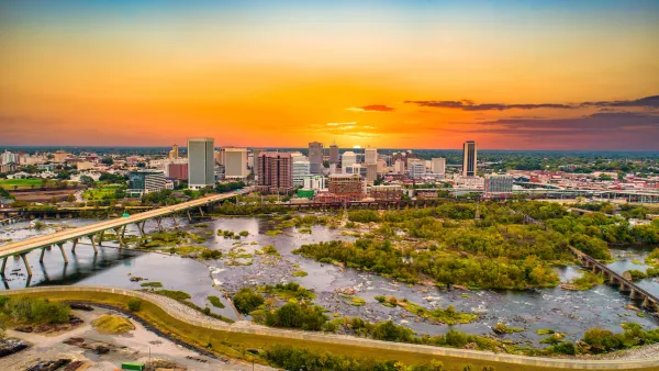 Aerial view of Richmond, Virginia skyline with river in foreground against sunset sky.