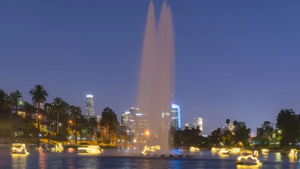 View of Echo Park Lake at night with artesian fountain and illuminated swan paddle boats and Los Angeles skyline in background