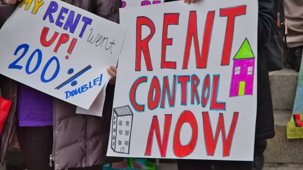 Close-up of "Rent Control Now" sign being held up at a protest.
