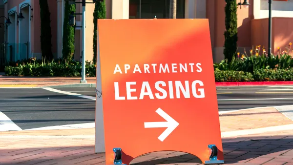 Orange "Apartments Leasing" sandwich board sign on sidewalk with arrow pointing right.
