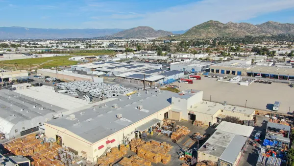 Aerial view of large warehouses in Southern California with hills in background.