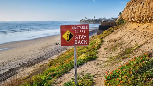 Red "Unstable Cliffs - Stay Back" sign on tall Pacific coast cliff