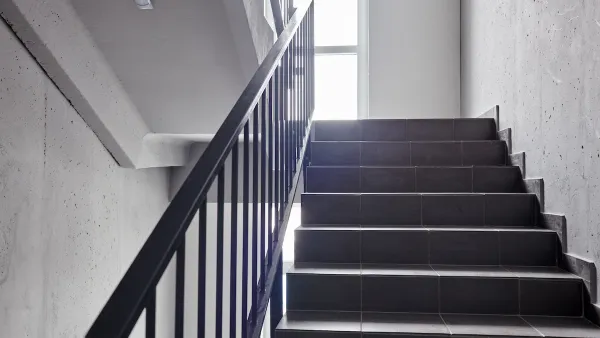 View of plain building staircase with light coming in from window on landing
