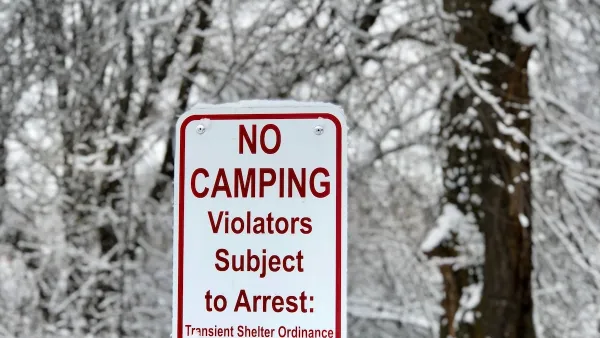 White sign with No Camping - Violators Subject to Arrest and municipal code in red text with snowy trees in background.