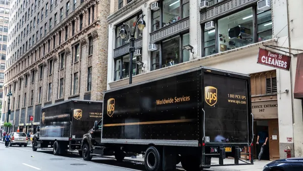 Two brown UPS trucks parked at curbside on New York City street.