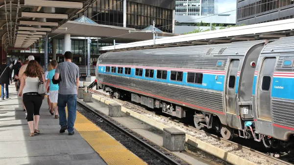 Passengers walking on platform at Boston train station with Amtrak train parked on track.