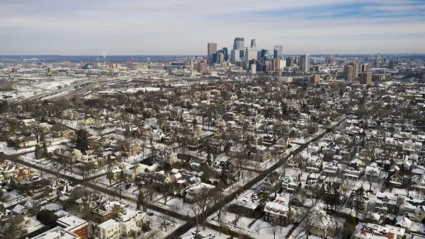 Aerial view of Minneapolis neighborhood and downtown skyline in winter with snow.