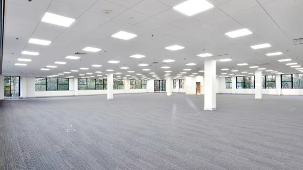 Large empty office building floor with white walls and grey carpeting