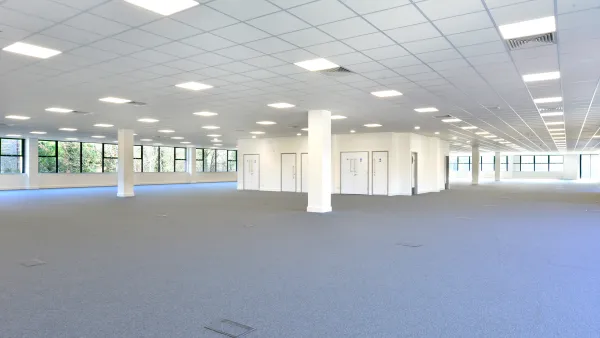 Empty open plan office with gray carpet and white walls