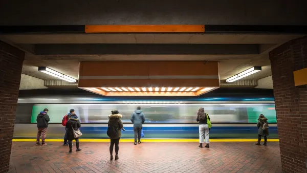 People waiting on subway platform with blurred train passing by.