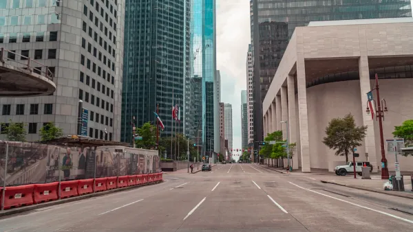 Large brutalist building and skyscrapers viewed from middle of wide street in downtown Houston, Texas.