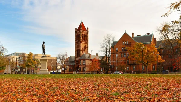 John Bridge Monument (also known as The Puritan), in the northeast corner of the Cambridge Common in Cambridge, Massachusetts with fall foliage on ground.