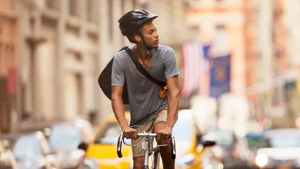 Man riding bicycle wearing black helmet on New York City street.