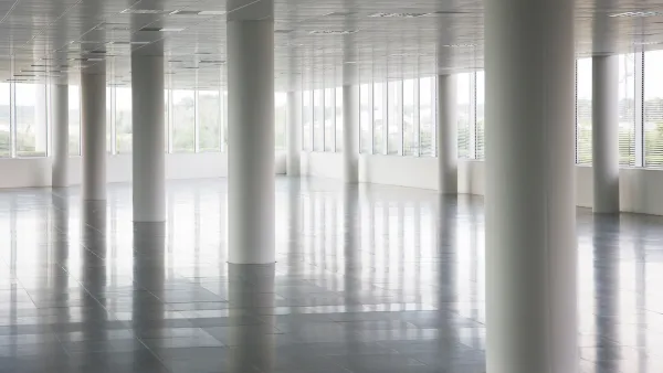 White round pillars in empty office building with windows across all walls and white floors and ceiling.