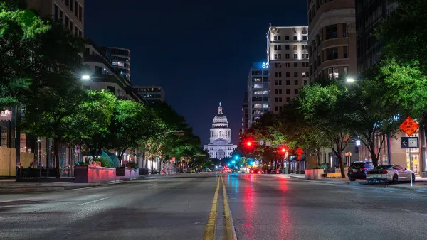 Low angle view of Texas state capitol at night from middle of wide street.