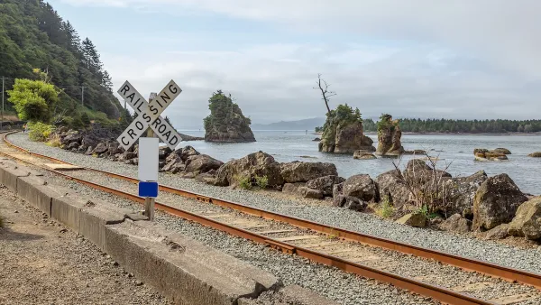 Railroad crossing sign next to tracks along rocky coast in Oregon.