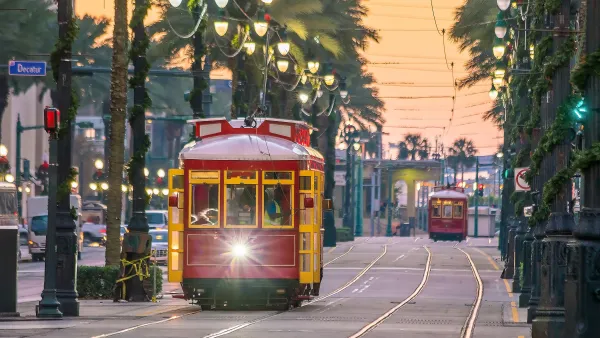 Red and yellow New Orleans streetcar running down street lined with palm trees