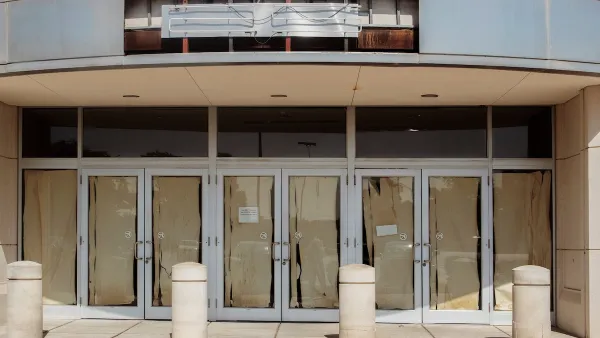 Vacant retail storefront with multiple glass doors lined with brown paper and a removed neon sign.