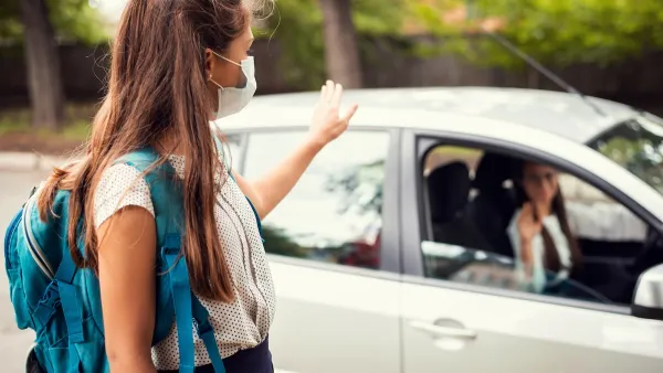 Girl wearing Covid mask and backpack getting dropped off by mom at school.