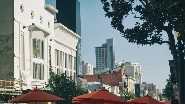 The tops of umbrellas for outdoor dining spaces are visible with large buildings in the background on a sunny day in the city of San Diego.