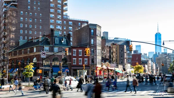 Street scene in Greenwich Village, New York City with people walking through busy intersection and new WTC tower in background.