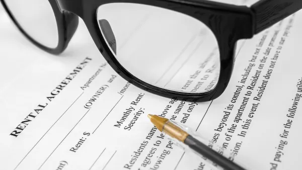 Close-up of rental agreement with pen and black-rimmed glasses.