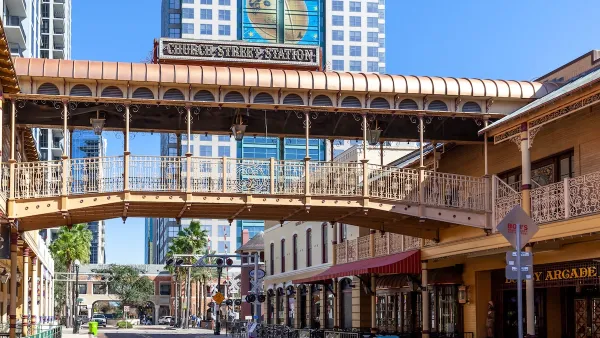 Commercial street in Orlando, Florida with elevated pedestrian walkway crossing the street at Church Street Station historic train station and commercial hub.