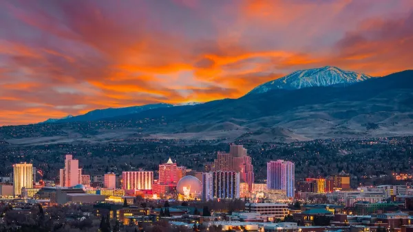 Skyline of Reno, Nevada against snowy mountains and bright red sunset sky.