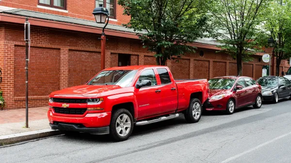 Red Chevrolet truck parked on street in front of two small sedans in Philadelphia, Pennsylvania.