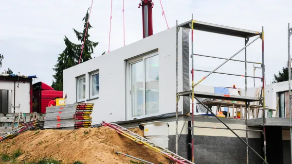 White modular home being built on dirt mound