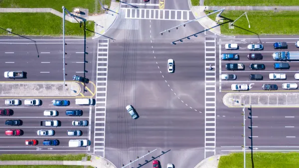 Bird-s eye view of multi-lane road intersection with medians and crosswalks.