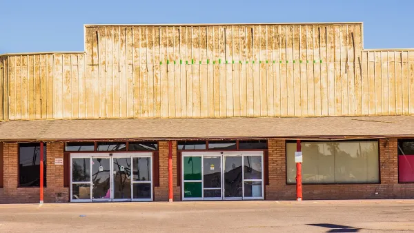 One-story vacant Western-style strip mall with blocked windows.