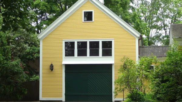Yellow converted garage with green door and white-framed windows.