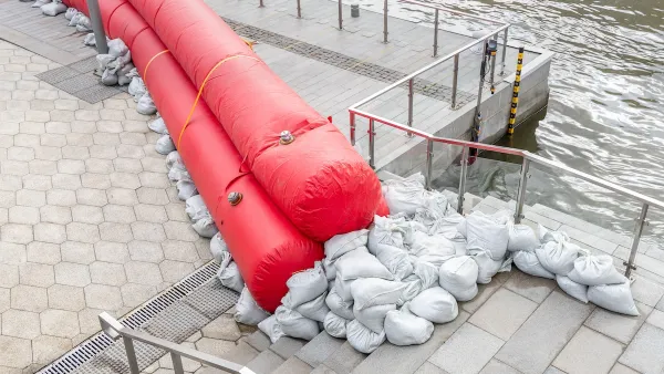 Sandbags and red water-filled cylinders lined up on a concrete pier to prevent flooding.