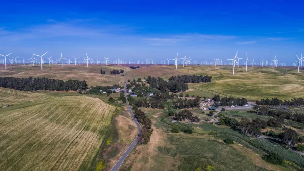 Aerial view of small community among green agricultural fields and wind turbines in Solano County, Northern California.