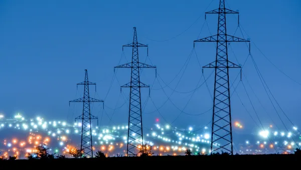 Tall power line towers with blurred city lights in background.