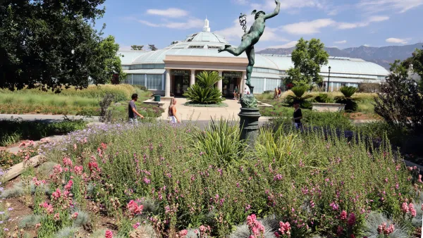 Glass-topped conservatory building with bronze statue in foreground at Los Angeles County Arboretum and Botanic Garden