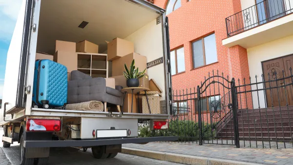 Moving truck with open back door with furniture and a blue suitcase visible inside.