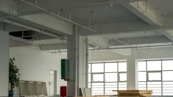 Vacant interior of open plan office with large buildings and stacked wood planks on floor.