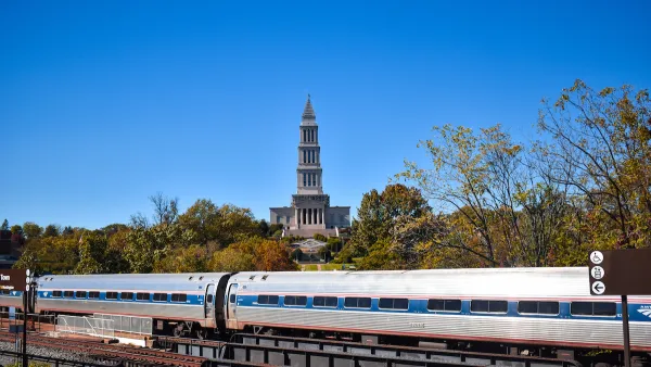 Amtrak train passing on bridge with historic tower in background in Alexandria, Virginia.