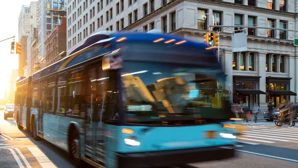 Blue and green city bus blurred in transit on New York City street.