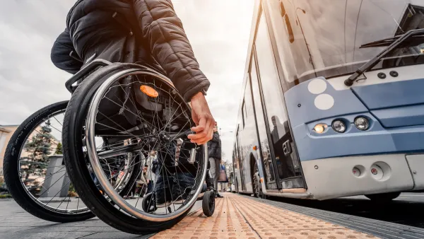 Ground-up view of man using wheelchair waiting to board a light blue bus.