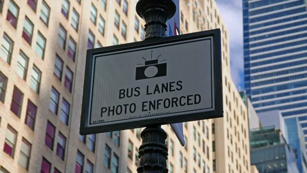 Close-up of "Bus Lanes - Photo Enforced" sign with camera logo on New York City street pole.
