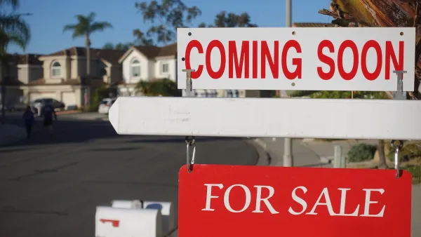 Close-up on red and white "Coming Soon" and "For Sale" signs in front of single-family homes on sunny day.