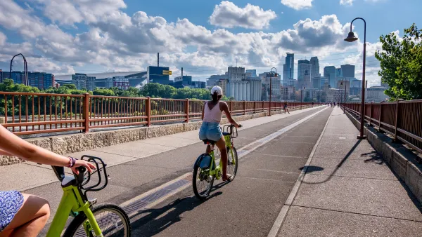 People on bike share bikes on bridge with Minneapolis, Minnesota skyline in background